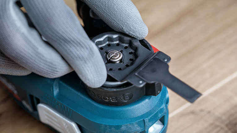 Una persona che indossa un equipaggiamento di sicurezza regola un accessorio su un elettroutensile.