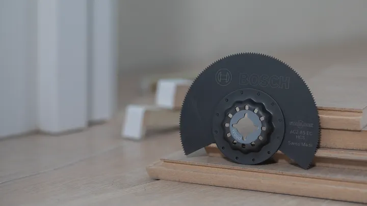 Lama multiutensile oscillante posizionata su assi di legno impilate.