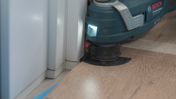 Utensile multiuso oscillante per tagliare pavimenti laminati vicino all'angolo di una parete.