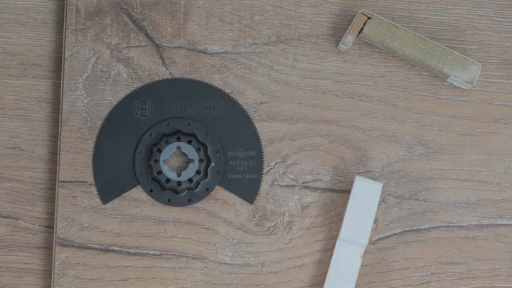 Lama di sega circolare e imballaggio appoggiati su una superficie con texture in legno.