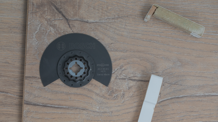 Lama di sega circolare e imballaggio appoggiati su una superficie con texture in legno.