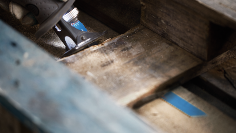 Una persona usa un elettroutensile per tagliare un pallet di legno.