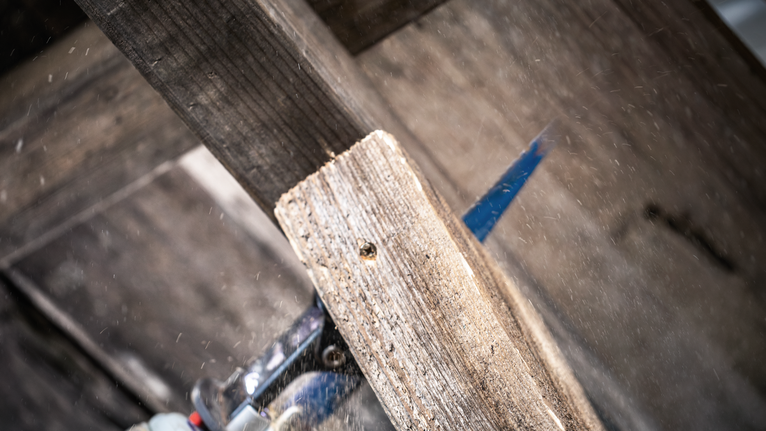 Taglio con il seghetto alternativo di una tavola di legno all'aperto.