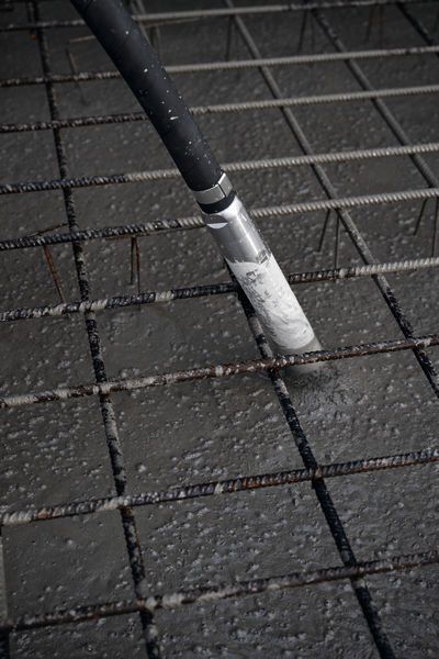 Vibratore per calcestruzzo che consolida il calcestruzzo appena colato su una griglia di rinforzo in acciaio.