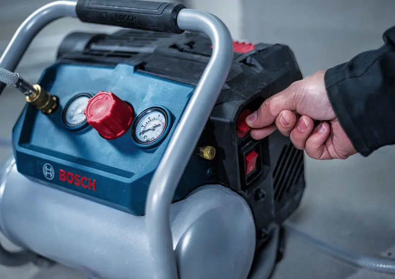 Una persona accende un compressore d'aria portatile in un ambiente di lavoro al chiuso.