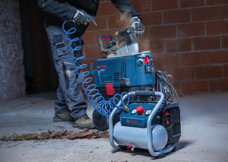 Una persona che indossa un equipaggiamento di sicurezza utilizza un compressore d'aria portatile collegato a una sega.