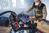 Una persona che indossa dispositivi di protezione individuale utilizza una sega a troncare per tagliare una tavola di legno.