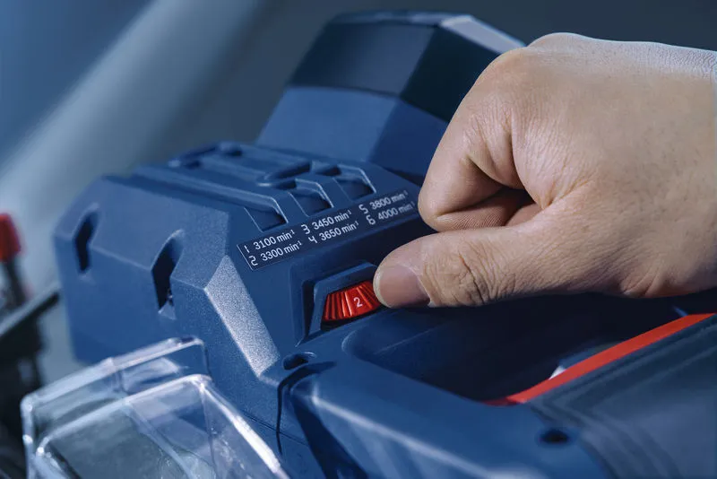 Una persona regola la velocità di una sega troncatrice.