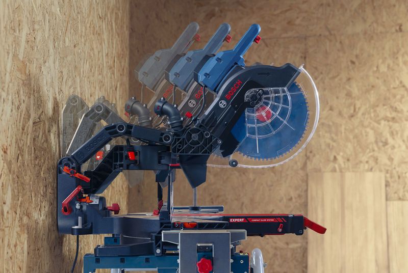 In un'officina, una sega a troncare regola gli angoli contro uno sfondo di legno.