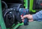 Una persona utilizza un trapano a percussione senza fili su un'attrezzatura meccanica.