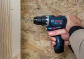 Una persona utilizza un trapano avvitatore a impulsi senza fili per fissare una vite a una tavola di legno.