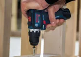 Una persona utilizza un trapano avvitatore a impulsi senza fili per avvitare una vite in una cornice di legno.