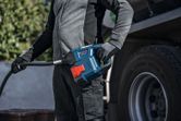 Una persona che indossa dispositivi di protezione individuale rifornisce di carburante un camion utilizzando una pompa portatile.