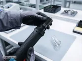 In un laboratorio di elettronica, una persona con indosso dispositivi di protezione individuale regola un avvitatore a batteria.