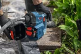 Una persona che indossa dispositivi di protezione individuale utilizza un utensile elettrico su una pietra da giardino.