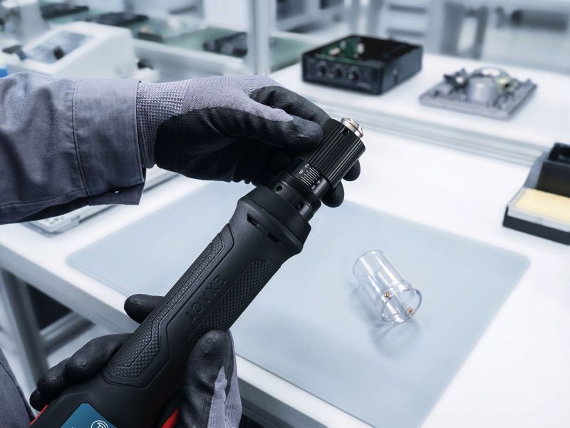 In un laboratorio di elettronica, una persona con indosso dispositivi di protezione individuale regola uno strumento di precisione.