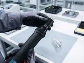 In un laboratorio di elettronica, una persona con indosso dispositivi di protezione individuale regola uno strumento di precisione.