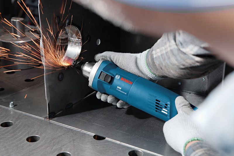 Una persona che indossa un equipaggiamento di sicurezza smeriglia un bordo metallico con un utensile elettrico, creando scintille.