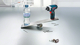 Une perceuse-visseuse sans fil Bosch Professional et une bouteille d'eau sur une surface métallique.