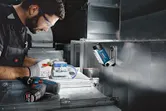 Una persona que usa equipo de seguridad trabaja con cableado eléctrico bajo una luz de trabajo inalámbrica.
