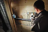 Una persona que usa equipo de seguridad trabaja con cableado eléctrico bajo una luz inalámbrica brillante.