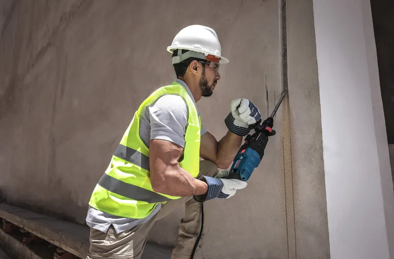 Una persona que usa equipo de seguridad utiliza una sierra alternativa para cortar una pared de hormigón.