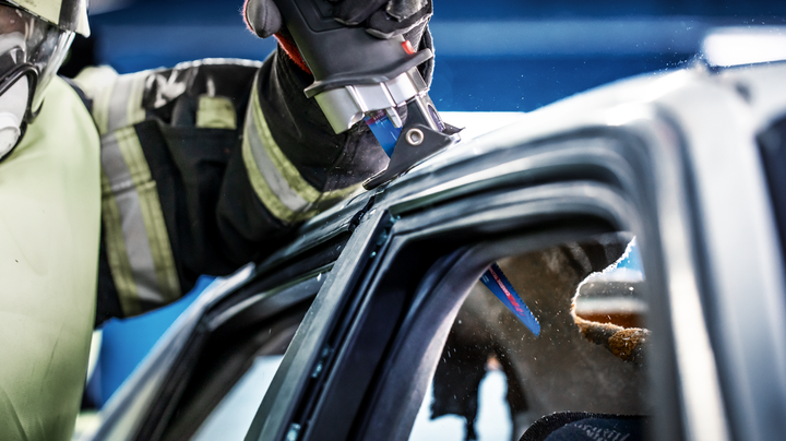 Una persona que usa equipo de seguridad corta el techo de un automóvil utilizando una sierra alternativa.