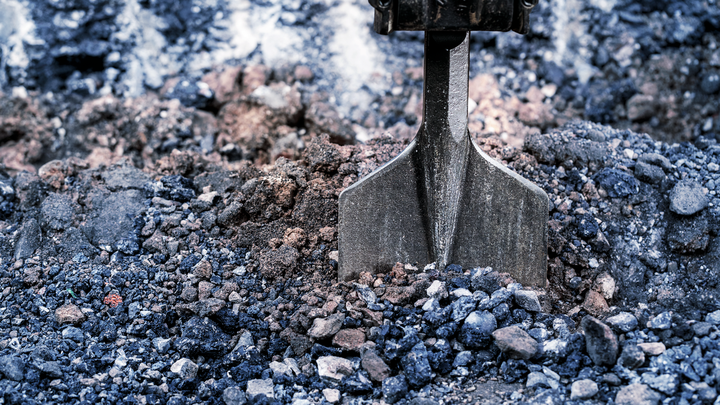 Broca de cincel rompiendo grava compactada en un sitio de construcción.