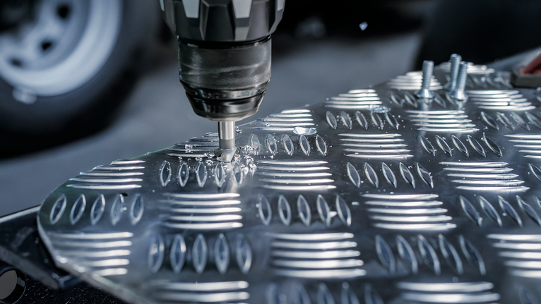 Taladro inalámbrico haciendo un agujero en una lámina de metal con placa de diamante.