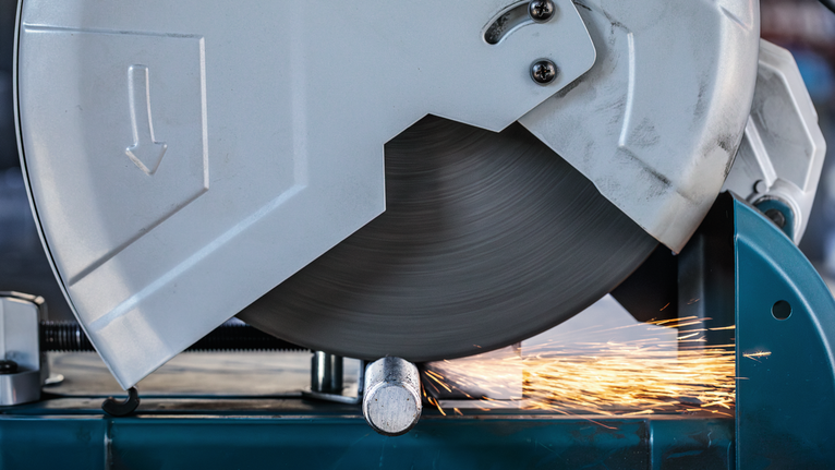 Sierra para cortar metal cortando una tubería mientras saltaban chispas brillantes.