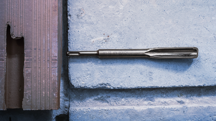 Broca de cincel colocada sobre una superficie de bloque de hormigón.