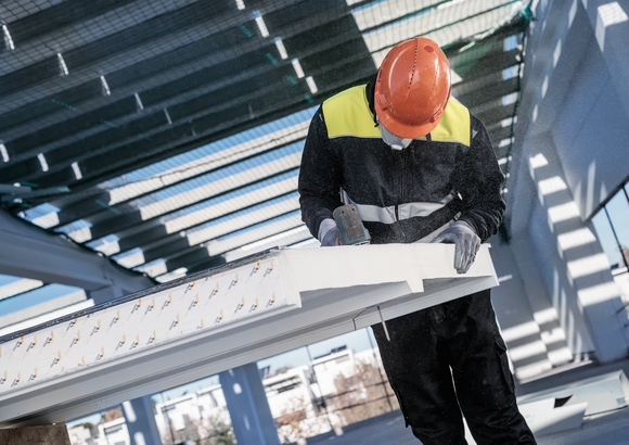 Una persona que usa equipo de seguridad utiliza una herramienta eléctrica para cortar una viga de construcción.