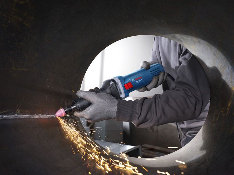 Una persona que usa equipo de seguridad utiliza una amoladora recta para alisar el interior de un tubo de metal.