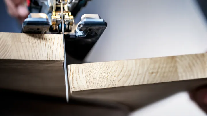 Una persona corta una tabla de madera con una sierra de calar.