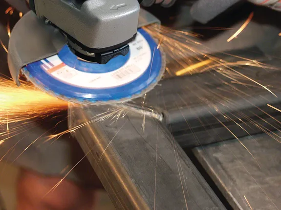 Amoladora angular cortando metal con chispas volando.