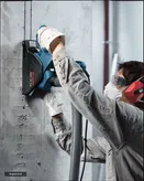 Una persona que usa equipo de seguridad utiliza una fresadora de pared para cortar un canal en el hormigón.