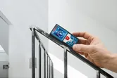 Una persona mide el ángulo de la barandilla de una escalera con un medidor láser.