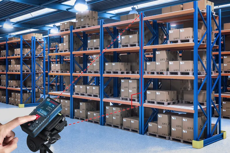 Una persona utiliza un medidor láser para comprobar las distancias entre los estantes del almacén.