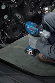 Una persona que usa equipo de seguridad instala un altavoz en la puerta de un automóvil utilizando una herramienta eléctrica inalámbrica.