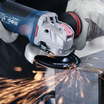 Un trabajador que usa equipo de seguridad muele metal, creando chispas con una amoladora angular.