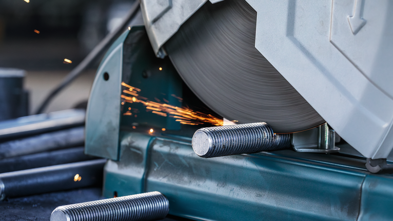 Sierra para cortar metales cortando varillas de acero, haciendo saltar chispas.