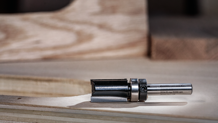 Broca fresadora de metal apoyada sobre una superficie de trabajo de madera.