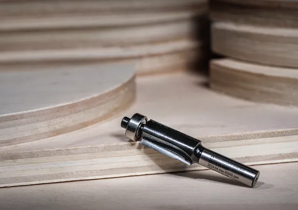 Broca de enrutador colocada sobre madera contrachapada en capas, lista para aplicaciones de carpintería.