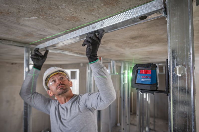 Una persona equipada con equipo de seguridad alinea una estructura metálica utilizando una herramienta de nivelación láser.