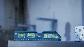 Un nivel de burbuja azul descansa sobre una superficie metálica en una obra de construcción.