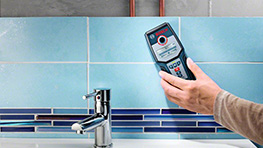 Un medidor Bosch Professional azul en una cocina junto a un grifo de metal brillante.