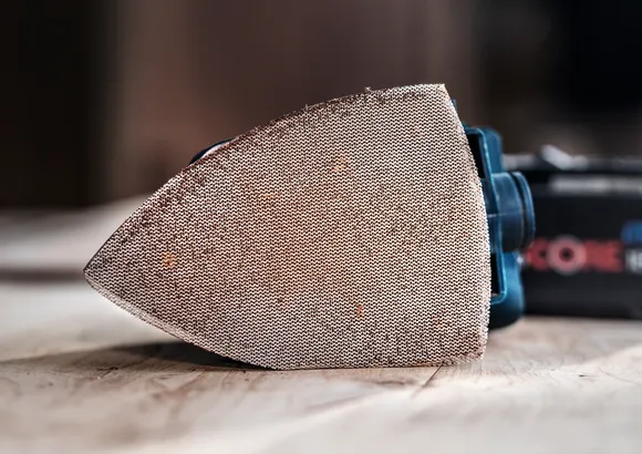 Detailní pohled na brusný kotouč připevněný k elektrickému nářadí na dřevěném povrchu.