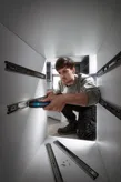Osoba používá akumulátorový šroubovák k instalaci výsuvů zásuvek uvnitř skříňky.