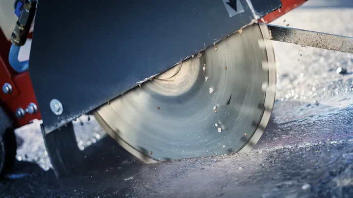 Velká kotoučová pila řezající mokrý beton na staveništi.