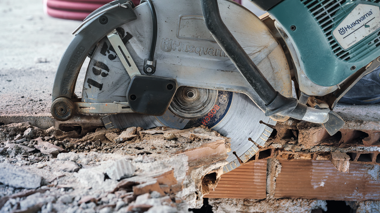 Velká kotoučová pila řeže beton a rozptyluje prach a nečistoty.